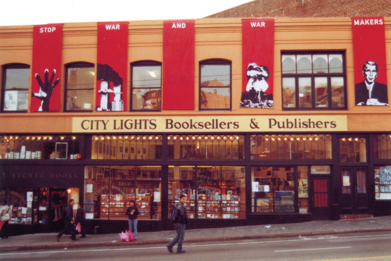 Few people walk by the City Lights storefront that is decorated with large red banners